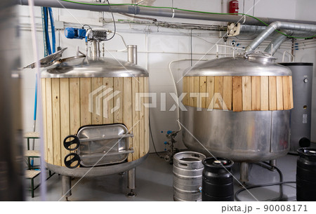 Steel fermenters with wood trim and kegs in brewery Steel fermenters with wood trim and kegs in brewery 90008171