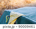 Roof of tourist tent under the morning sun. Green waterproof fabric was covered with cold and condensation from frost. Equipment for survival in wild 90009461