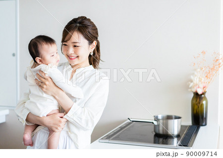 赤ちゃんを抱っこしながら家事をする若い女性 赤ちゃんを抱っこしながら家事をする若い女性 90009714