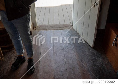 Person's feet inside entrance of open door with antique wood floors Person's feet inside entrance of open door with antique wood floors 90010002