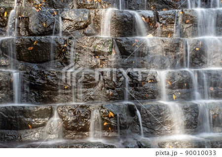 Water cascades over black rocks in tiered waterfall Water cascades over black rocks in tiered waterfall 90010033