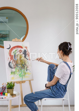 Creative of art concept, Young asian woman holding paintbrush and contemplate about the artwork 90012008