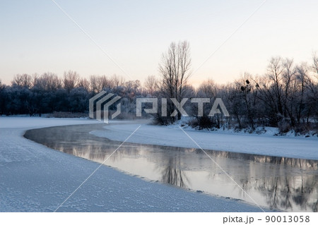 Photo the snow-covered river did not freeze in winter.The river flows in winter. Snow on the branches of trees. Reflection of snow in the river. Huge snowdrifts lie on the Bank of the stream. Photo the snow-covered river did not freeze in winter.The river flows in winter. Snow on the branches of trees. Reflection of snow in the river. Huge snowdrifts lie on the Bank of the stream. 90013058