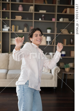 Vertical view, young woman dancing listening music through earbuds Vertical view, young woman dancing listening music through earbuds 90014127