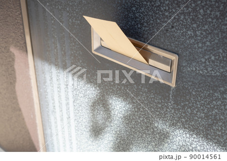 玄関の郵便受けに入れられた封筒 90014561
