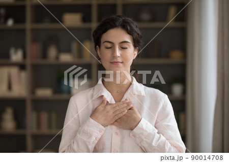 Woman put folded palms on chest feels grateful 90014708