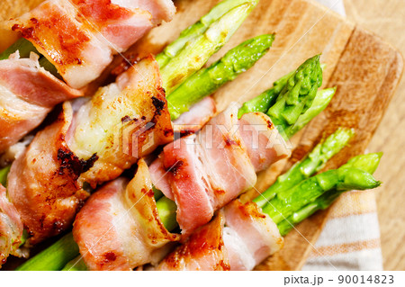 Bacon wrapped asparagus on wooden plate. Bacon wrapped asparagus on wooden plate. 90014823