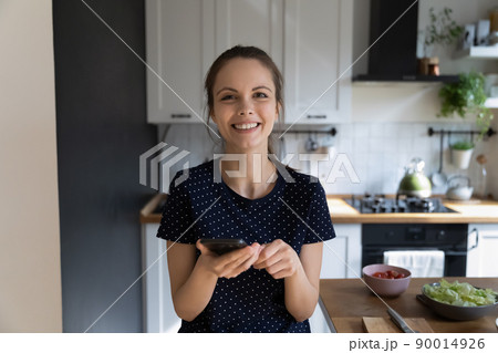 Happy cook blogger woman using mobile phone at kitchen table Happy cook blogger woman using mobile phone at kitchen table 90014926