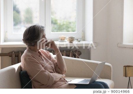 Thoughtful frustrated mature 60s woman holding laptop computer Thoughtful frustrated mature 60s woman holding laptop computer 90014966