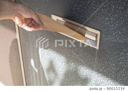 玄関の郵便受けに封筒を入れる手 玄関の郵便受けに封筒を入れる手 90015234
