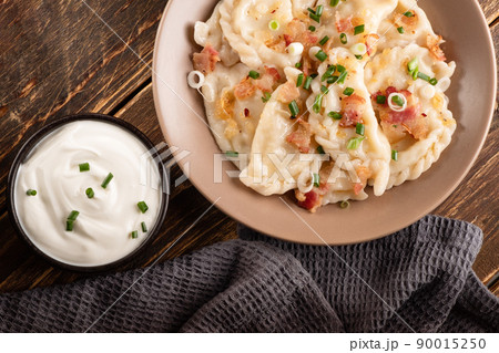 Potato dumplings with sour cream on the wooden table. Traditional ukrainian food. Varenyky, vareniki, pierogi, pyrohy - dumplings with filling. Potato dumplings with sour cream on the wooden table. Traditional ukrainian food. Varenyky, vareniki, pierogi, pyrohy - dumplings with filling. 90015250