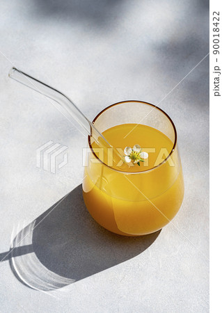 Glass of orange juice with glass straw sun light. Minimalist style 90018422
