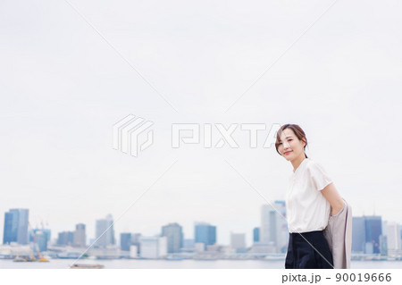 都会でジャケットを脱ぐビジネスウーマン 90019666