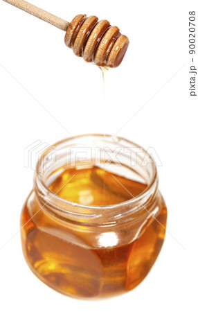 Honey dripping from honey dipper in glass jar. Healthy food concept 90020708