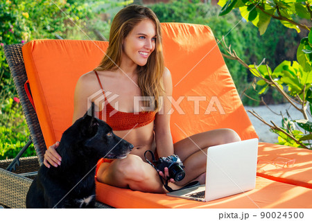 remote work on the beach freelancing girl in a coral bathing suit sitting in a lounge chair and the beach with a laptop.business lady online purchase black Friday sale on vacation in tropical country remote work on the beach freelancing girl in a coral bathing suit sitting in a lounge chair and the beach with a laptop.business lady online purchase black Friday sale on vacation in tropical country 90024500
