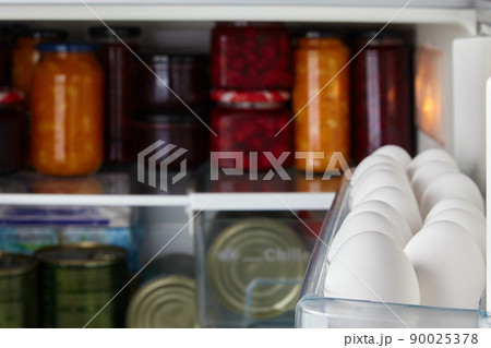 White raw chicken eggs in a tray of the refrigerator 90025378