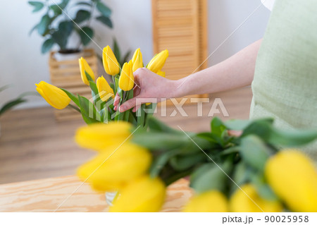 The florist places yellow tulips in a vase. Work in a flower shop. Blooming bright flowers The florist places yellow tulips in a vase. Work in a flower shop. Blooming bright flowers 90025958