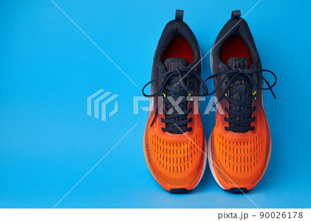 Orange sneakers on a blue background with copy space Orange sneakers on a blue background with copy space 90026178