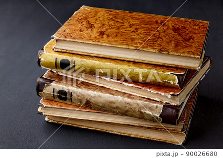 A stack of vintage dilapidated books on a dark concrete table A stack of vintage dilapidated books on a dark concrete table 90026680