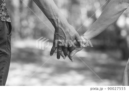 The husband's hand firmly holds the wife's hand close-up. Loving couple walking and holding hands. Reliable and strong marriage. The concept of romance, fidelity in marriage and love. Black and white The husband's hand firmly holds the wife's hand close-up. Loving couple walking and holding hands. Reliable and strong marriage. The concept of romance, fidelity in marriage and love. Black and white 90027555