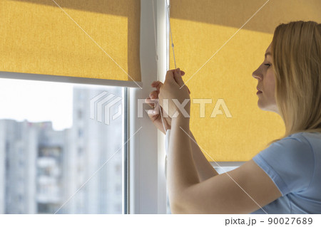 Closing blinds, roller blinds, from direct sunlight. Close up. Closing blinds, roller blinds, from direct sunlight. Close up. 90027689