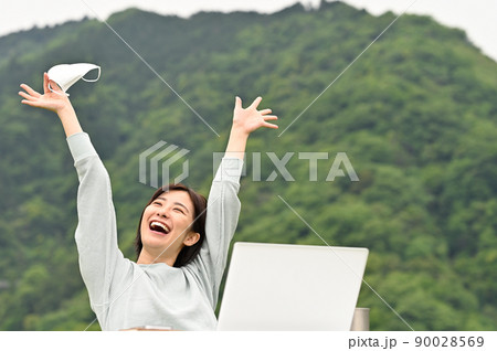 屋外でマスクを外して笑顔の女性 屋外でマスクを外して笑顔の女性 90028569