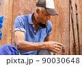 tired old afro american man sitting in the street 90030648