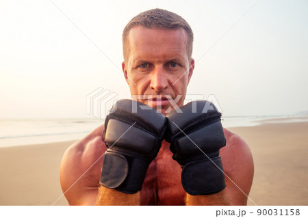 Strong boxer man doing during kickboxing exercise fight with trainer at sunset .close portrait of handsome fitness male model bodybuilder rage, anger and a splash of negative emotions Strong boxer man doing during kickboxing exercise fight with trainer at sunset .close portrait of handsome fitness male model bodybuilder rage, anger and a splash of negative emotions 90031158