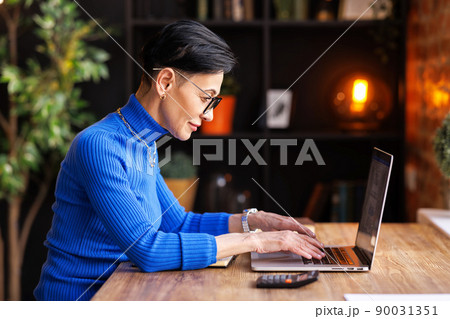 Mature businesswoman using laptop in home office Mature businesswoman using laptop in home office 90031351