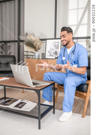 Joyous male physician conducting a video consultation 90032239