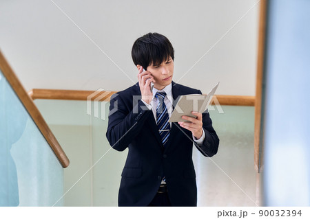 ノート片手にスマホで会話するビジネスマン ノート片手にスマホで会話するビジネスマン 90032394