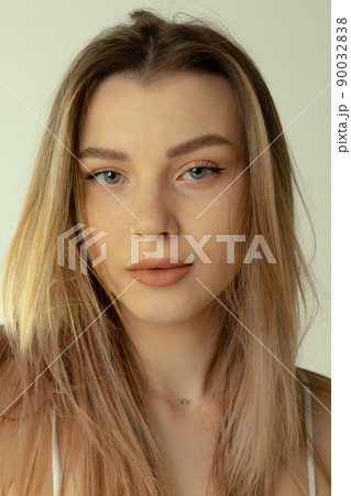 Close-up portrait of beautiful young blonde girl with natural makeup posing isolated over grey studio background Close-up portrait of beautiful young blonde girl with natural makeup posing isolated over grey studio background 90032838