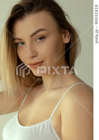 Close-up portrait of tender young blonde girl with natural makeup posing isolated over grey studio background Close-up portrait of tender young blonde girl with natural makeup posing isolated over grey studio background 90032839