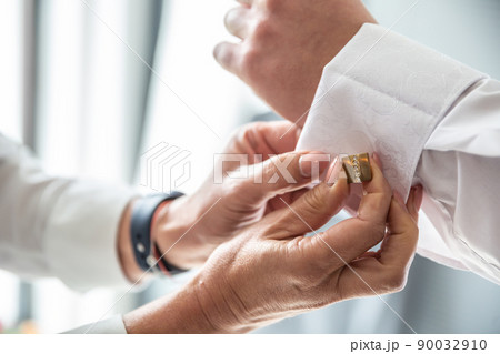 Best man helping groom fix cufflinks on his shirt before the wedding ceremony 90032910