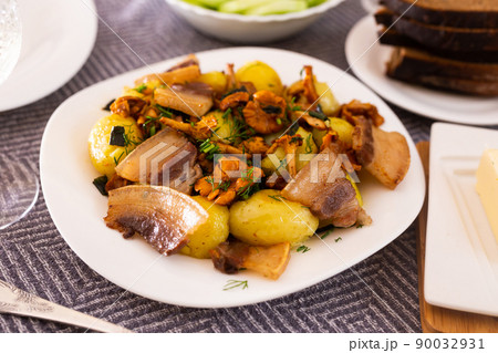 baked potatoes with chanterelles and bacon served with herbs on white plate 90032931
