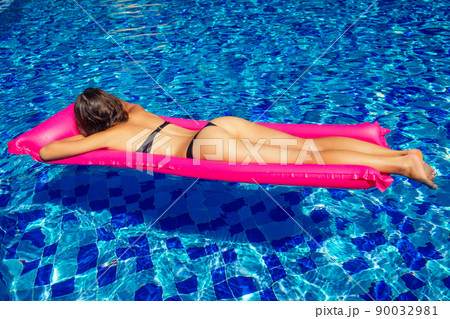 copy space spf and sunscreen beautiful brunette girl floating in the pool water.woman swimming and relaxing on pink inflatable mattress in blue swimmingpool remote work and freelance top view copy space spf and sunscreen beautiful brunette girl floating in the pool water.woman swimming and relaxing on pink inflatable mattress in blue swimmingpool remote work and freelance top view 90032981