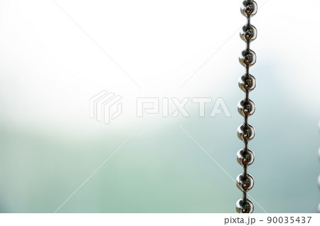 Close up a metal chain of a roller blind with blurred background for copy space. Close up a metal chain of a roller blind with blurred background for copy space. 90035437