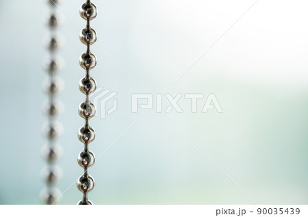 Close up a metal chain of a roller blind with blurred background for copy space. Close up a metal chain of a roller blind with blurred background for copy space. 90035439