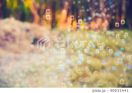 Abstract blurred of rainbow soap bubbles from the bubble blower flying on green grass. spring or summer season background. symbol of childhood. bokeh background. Abstract blurred of rainbow soap bubbles from the bubble blower flying on green grass. spring or summer season background. symbol of childhood. bokeh background. 90035441