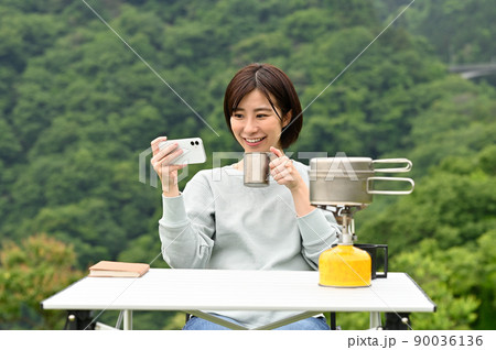 屋外でコーヒーを飲みながらスマホを見る女性 屋外でコーヒーを飲みながらスマホを見る女性 90036136
