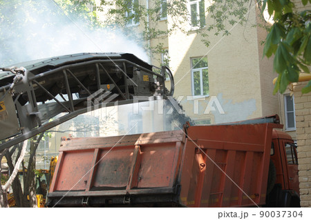 Road milling vehicle removes old asphalt and loads milled asphalt into dump truck. 90037304