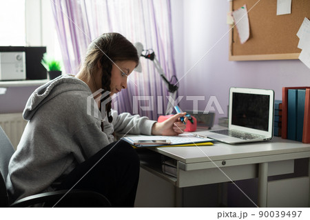 A student is sitting at her desk doing schoolwork. 90039497