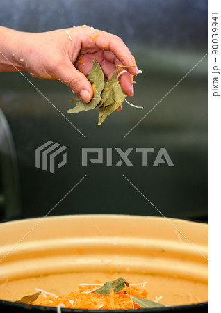 The process of cooking sauerkraut with carrots and bay leaves, close-up of hands and vegetables. The process of cooking sauerkraut with carrots and bay leaves, close-up of hands and vegetables. 90039941