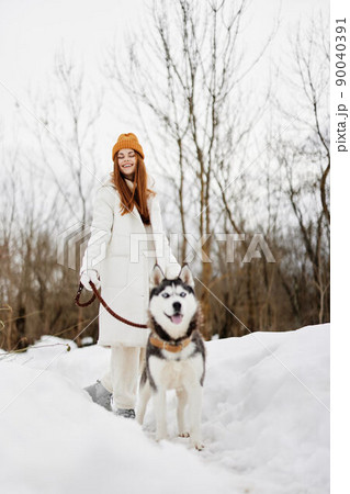 cheerful woman winter clothes walking the dog in the snow winter holidays 90040391