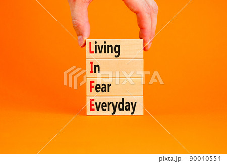 LIFE living in fear everyday symbol. Concept words LIFE living in fear everyday on wooden blocks on an orange background. Businessman hand. Business LIFE living in fear everyday concept. Copy space. LIFE living in fear everyday symbol. Concept words LIFE living in fear everyday on wooden blocks on an orange background. Businessman hand. Business LIFE living in fear everyday concept. Copy space. 90040554