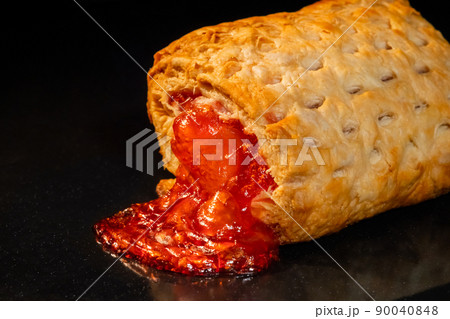 One baked bun with red strawberry jam on tray in electric oven, black background One baked bun with red strawberry jam on tray in electric oven, black background 90040848