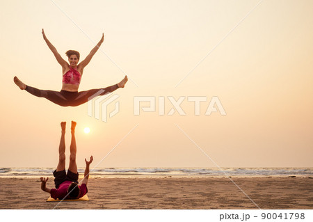 Two people practicing yoga in the sunset light on goa india beach. female and male acro yogi tantra flying copyspce Two people practicing yoga in the sunset light on goa india beach. female and male acro yogi tantra flying copyspce 90041798