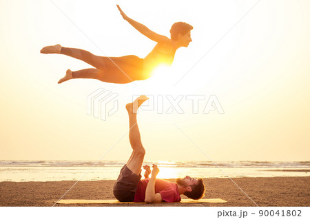 Two people practicing yoga in the sunset light on goa india beach. female and male acro yogi tantra flying copyspce Two people practicing yoga in the sunset light on goa india beach. female and male acro yogi tantra flying copyspce 90041802