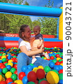 Baby girl lying down in colourful balls with mother 90043721