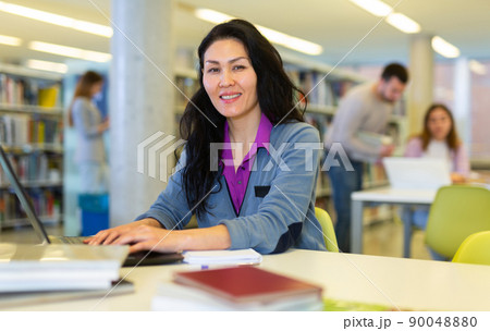 Focused woman working on laptop at library Focused woman working on laptop at library 90048880